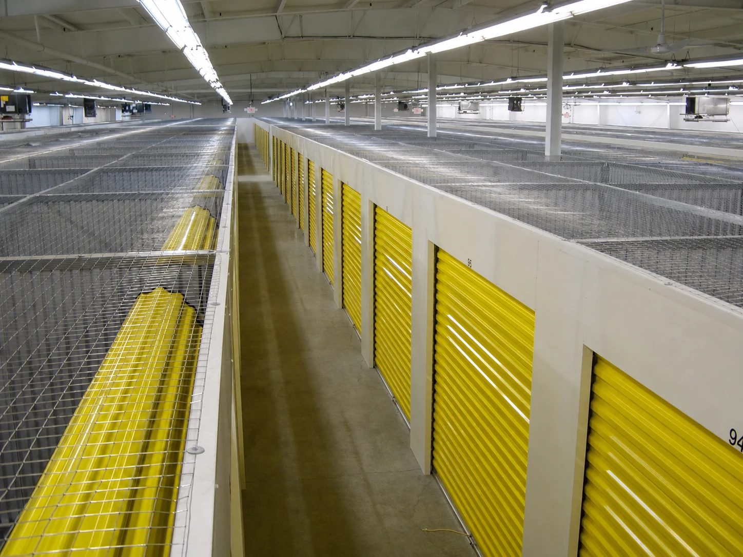 Self-storage conversion with yellow doors and open mesh ceilings