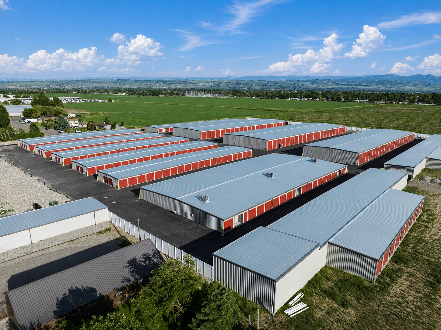 Aerial view of a large completed drive-up self-storage facility built by Johnson Construction, rows of buildings with red roll-up doors and metal roofs in a rural valley